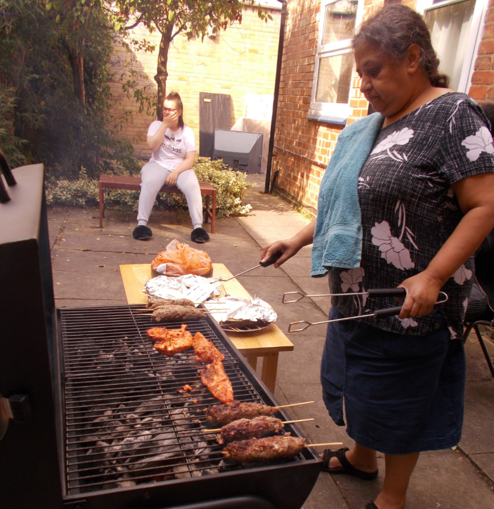 Naila, our office manager and support worker is outside in the buildings small garden, she his using a barbeque